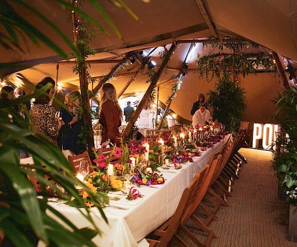 event in tent with long tables and wooden chairs