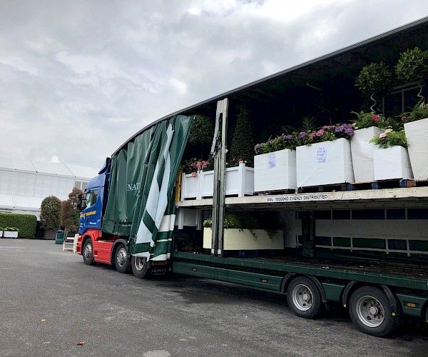 arctic lorry with curtain pulled back being loaded with planting for event